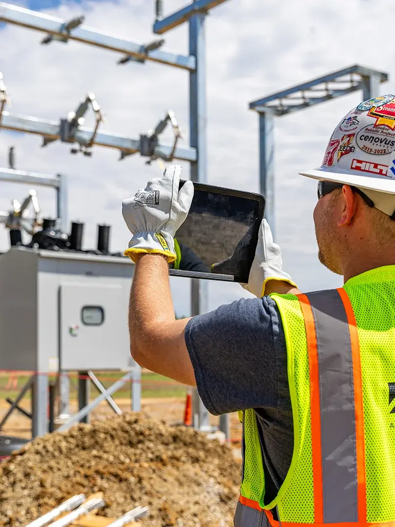 construction worker uses tablet to take photo of structure